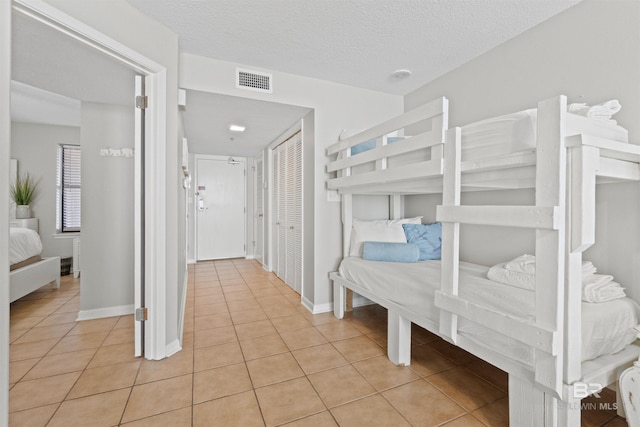 26802 Perdido Beach Blvd Unit 7C2, Orange Beach, AL 36561 - bedroom with a textured ceiling, baseboards, light tile patterned floors, visible vents, and a closet