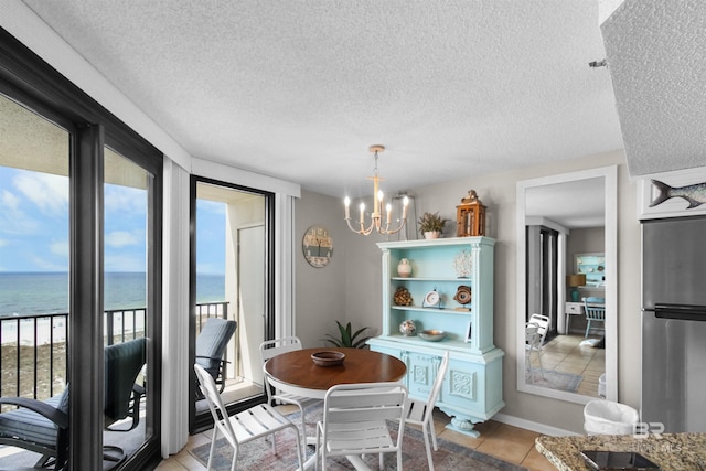 26802 Perdido Beach Blvd Unit 7C2, Orange Beach, AL 36561 - tiled dining space featuring a water view, a textured ceiling, a notable chandelier, and a healthy amount of sunlight