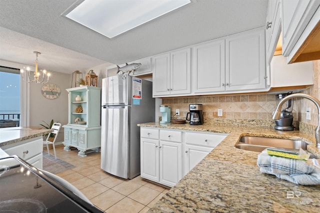 26802 Perdido Beach Blvd Unit 7C2, Orange Beach, AL 36561 - kitchen featuring tasteful backsplash, a sink, white cabinets, freestanding refrigerator, and light tile patterned flooring
