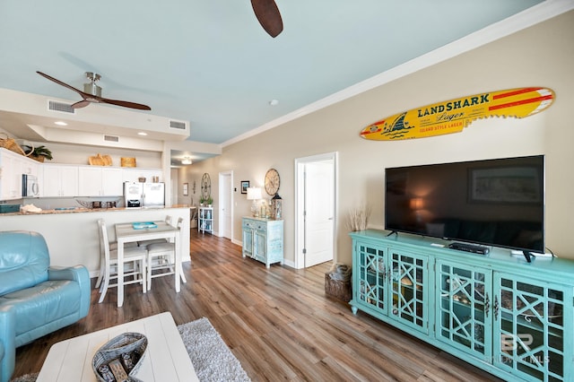 living area with visible vents, ornamental molding, a ceiling fan, and wood finished floors