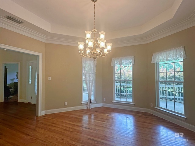 empty room featuring ornamental molding, a raised ceiling, a chandelier, and dark wood-type flooring