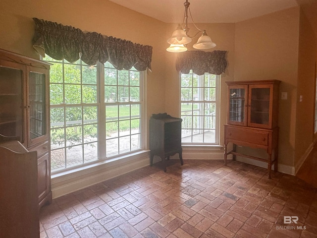 unfurnished dining area featuring a healthy amount of sunlight and a chandelier