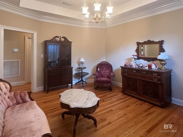 sitting room featuring crown molding, a notable chandelier, a tray ceiling, and hardwood / wood-style floors