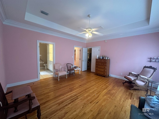 bedroom with ceiling fan, a tray ceiling, and hardwood / wood-style flooring