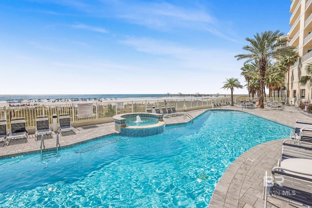 view of pool featuring a water view, pool water feature, a hot tub, and a patio area