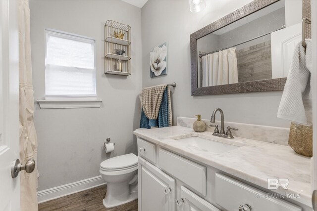 bathroom with vanity, wood finished floors, toilet, baseboards, and a shower with shower curtain