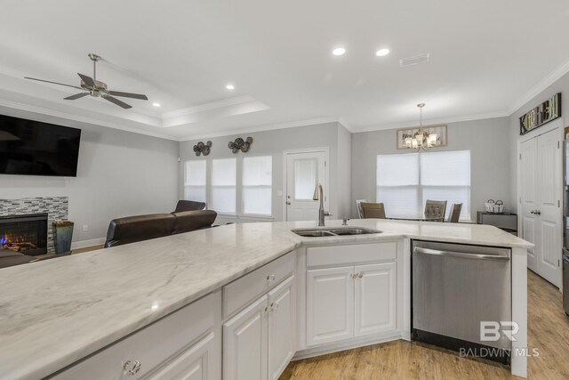 kitchen featuring stainless steel dishwasher, a fireplace, a sink, open floor plan, and white cabinetry