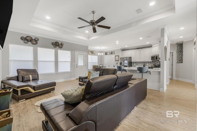 living area with visible vents, ceiling fan, recessed lighting, a tray ceiling, and light wood finished floors
