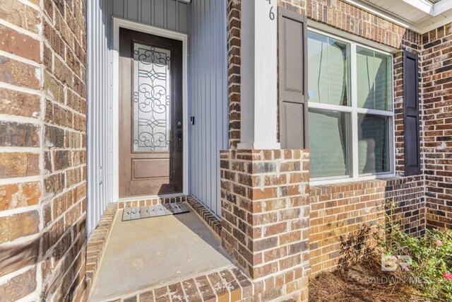view of exterior entry featuring covered porch and brick siding
