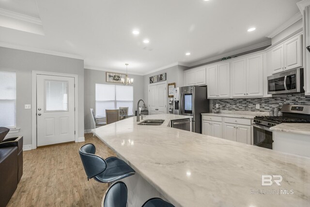 kitchen featuring a sink, stainless steel appliances, white cabinetry, and a chandelier