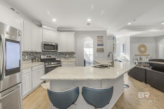 kitchen with a sink, appliances with stainless steel finishes, arched walkways, and open floor plan