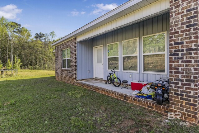 rear view of property with a lawn and brick siding