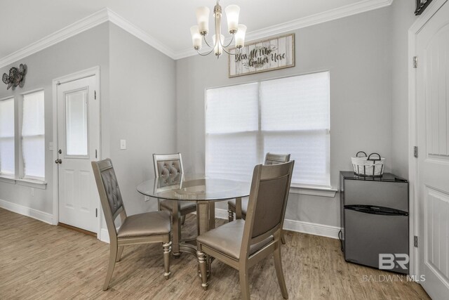 dining space featuring crown molding, light wood-style flooring, baseboards, and a notable chandelier