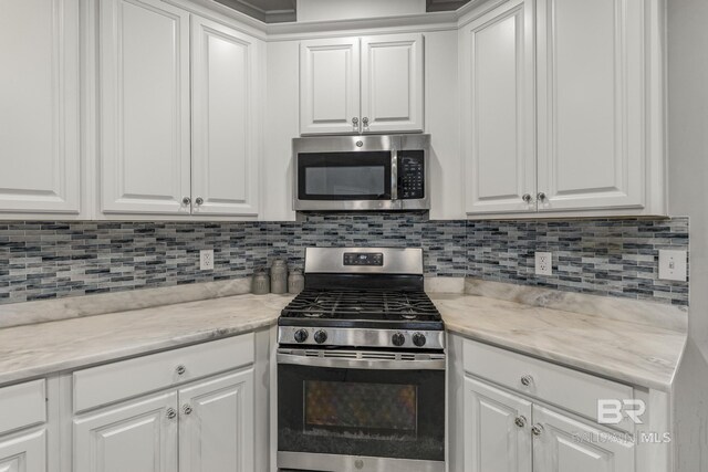 kitchen featuring white cabinets, stainless steel appliances, light stone countertops, and backsplash