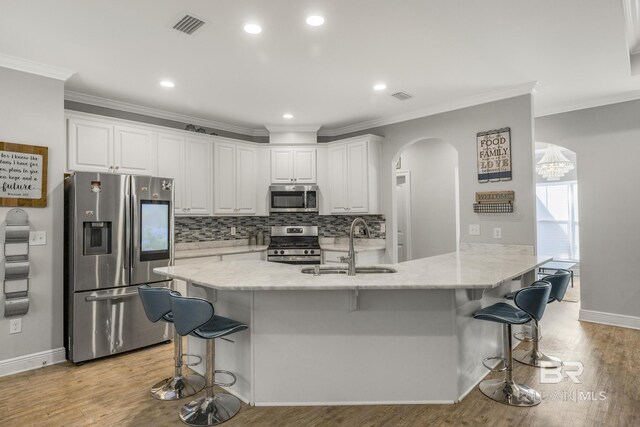 kitchen featuring a breakfast bar area, visible vents, arched walkways, a sink, and stainless steel appliances
