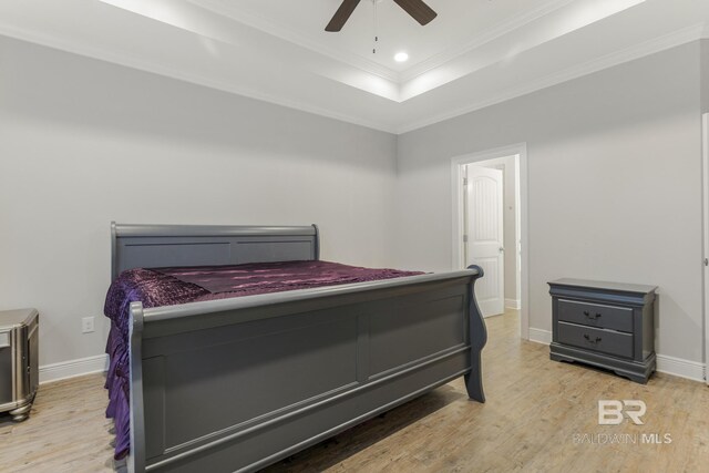 bedroom with ornamental molding, wood finished floors, baseboards, recessed lighting, and a raised ceiling