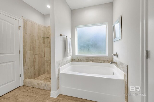 full bath with tiled shower, a bath, and wood finished floors