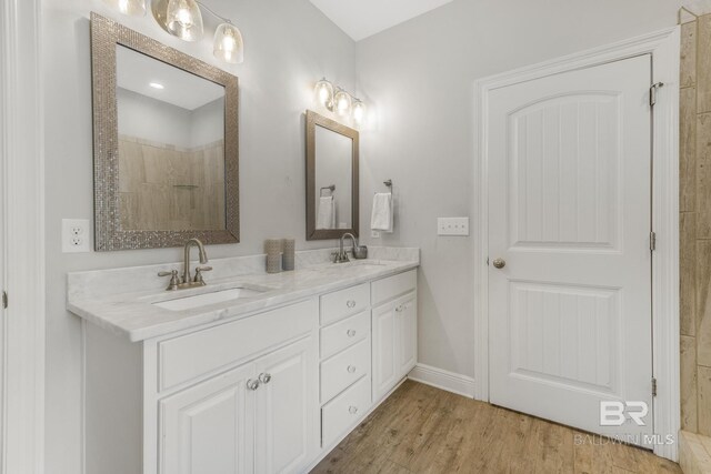 full bathroom featuring a sink, baseboards, double vanity, and wood finished floors