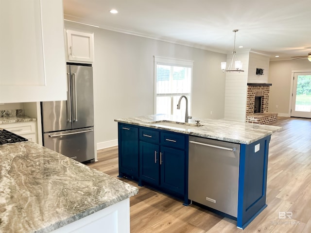 kitchen with a fireplace, stainless steel appliances, a healthy amount of sunlight, white cabinets, and light hardwood / wood-style flooring