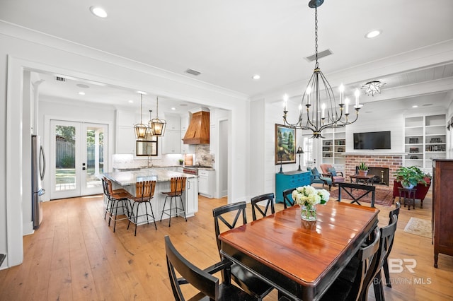 dining area with french doors, visible vents, crown molding, and light wood finished floors