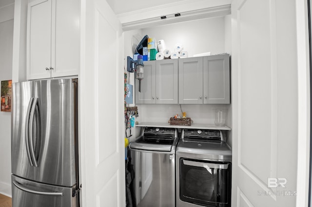 clothes washing area featuring cabinet space and washer and clothes dryer