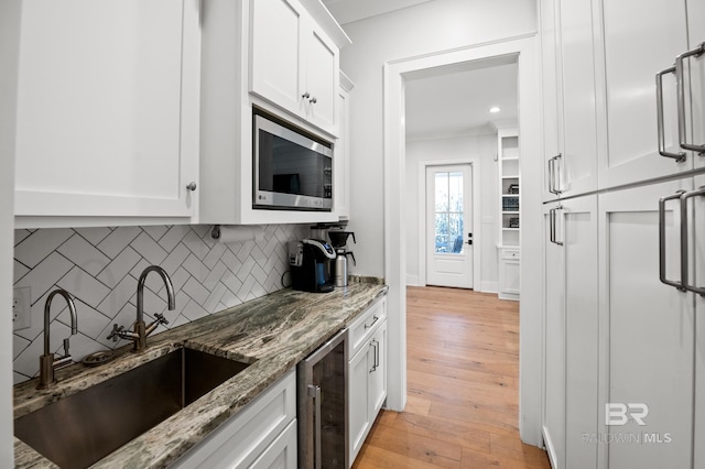 kitchen with stainless steel microwave, a sink, and white cabinetry