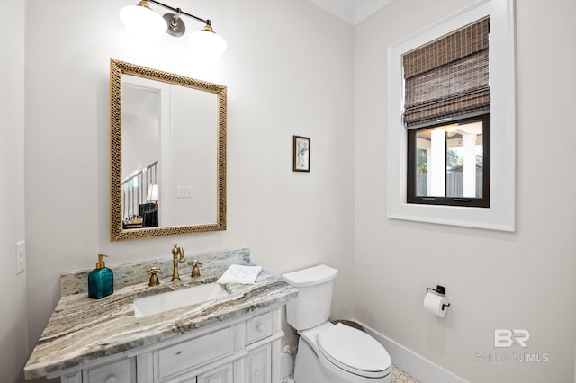 bathroom with baseboards, vanity, and toilet