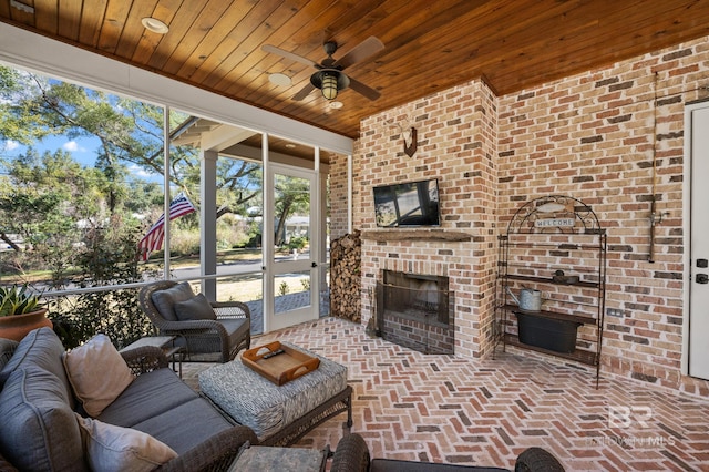 living area featuring ceiling fan, brick floor, a brick fireplace, and wood ceiling