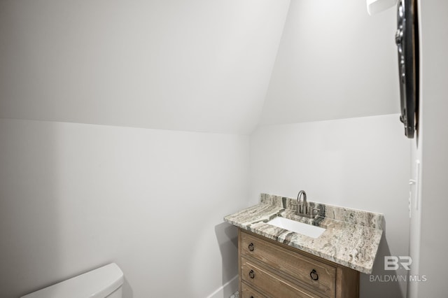 bathroom featuring lofted ceiling, vanity, and toilet