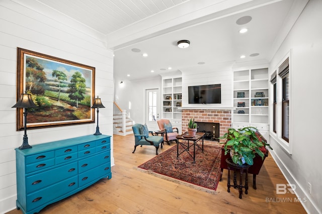 living area with ornamental molding, recessed lighting, a fireplace, and light wood-style flooring