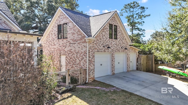 view of side of home with brick siding, a shingled roof, and fence