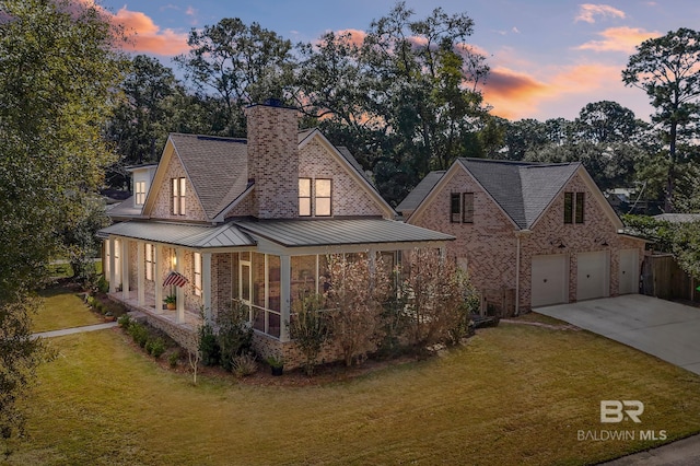 view of front of house featuring driveway, a front lawn, and a standing seam roof