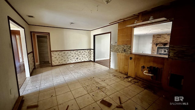 empty room with a wainscoted wall, visible vents, and ornamental molding