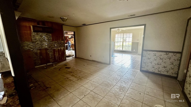 unfurnished room featuring ornamental molding, wainscoting, visible vents, and ceiling fan