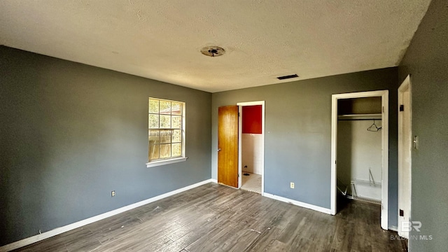 unfurnished bedroom featuring a closet, visible vents, baseboards, and wood finished floors