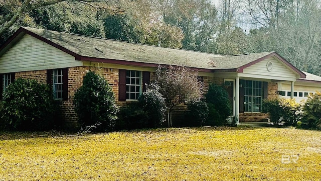 ranch-style home with a garage, brick siding, and a front yard