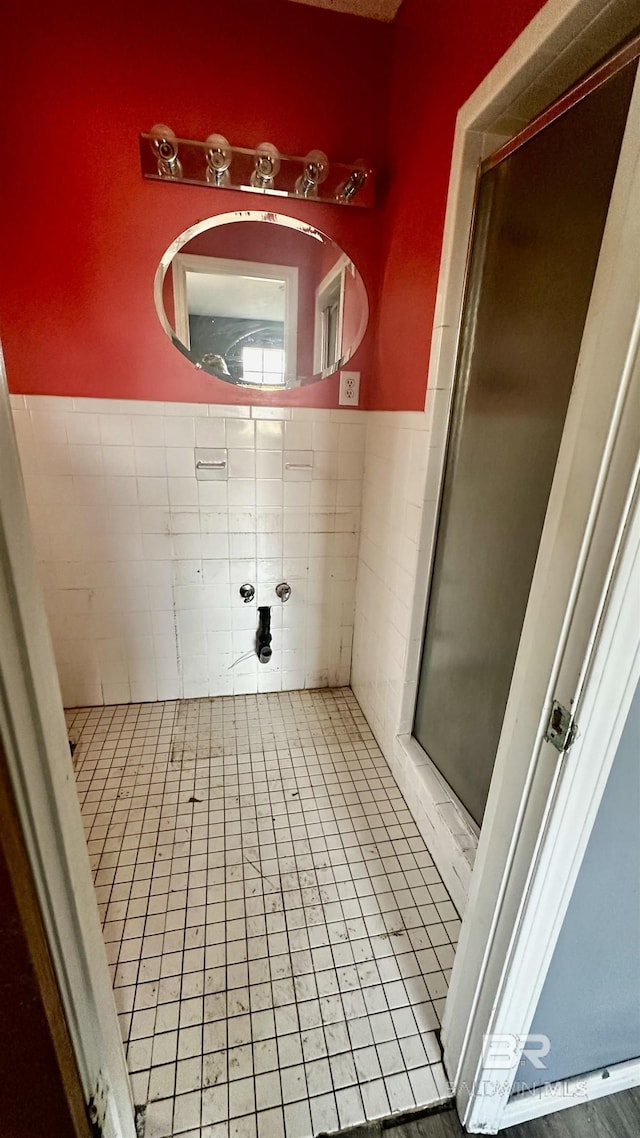 full bathroom with a stall shower, wainscoting, tile walls, and tile patterned floors