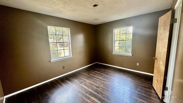 spare room with dark wood-style floors, a wealth of natural light, and baseboards