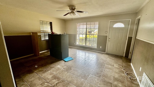 entryway featuring visible vents, a ceiling fan, ornamental molding, tile patterned flooring, and baseboards