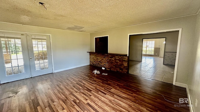 spare room with a textured ceiling, wood finished floors, and french doors