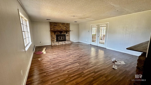 unfurnished living room with french doors, a fireplace, a textured ceiling, and wood finished floors