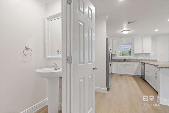 4310 Lauder Ln, Orange Beach, AL 36561 - bathroom with a sink, wood finished floors, baseboards, visible vents, and decorative backsplash