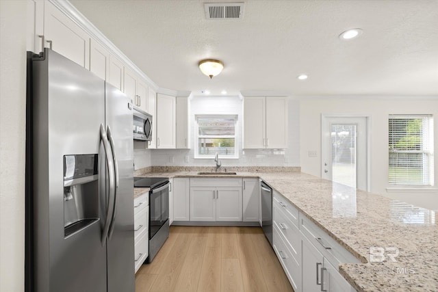 4310 Lauder Ln, Orange Beach, AL 36561 - kitchen with visible vents, stainless steel appliances, white cabinetry, a sink, and light wood-type flooring