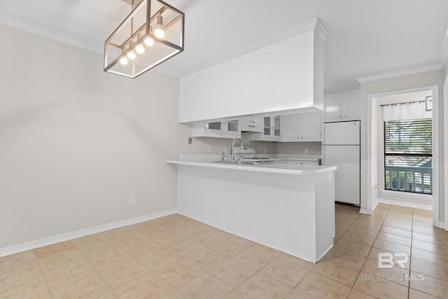 kitchen featuring freestanding refrigerator, crown molding, a peninsula, and a sink