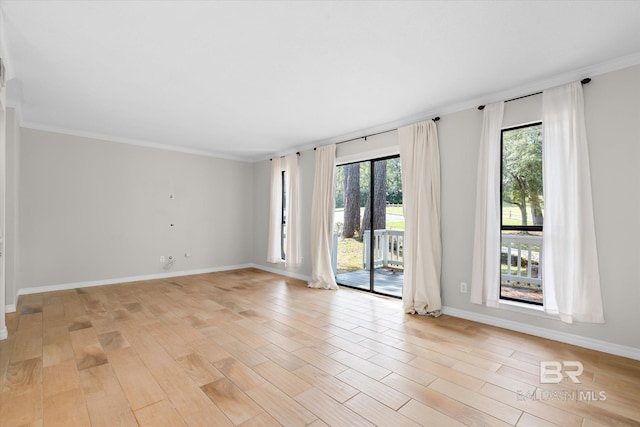 empty room featuring light wood-type flooring, baseboards, and ornamental molding