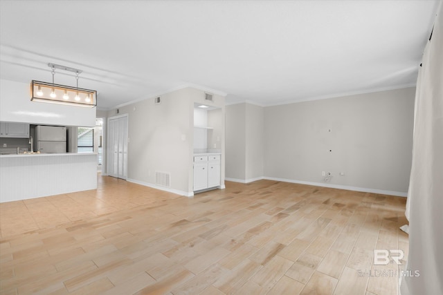 unfurnished living room with crown molding, rail lighting, visible vents, light wood-style flooring, and baseboards