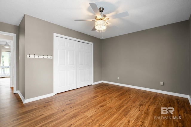 unfurnished bedroom featuring a closet, baseboards, and wood finished floors