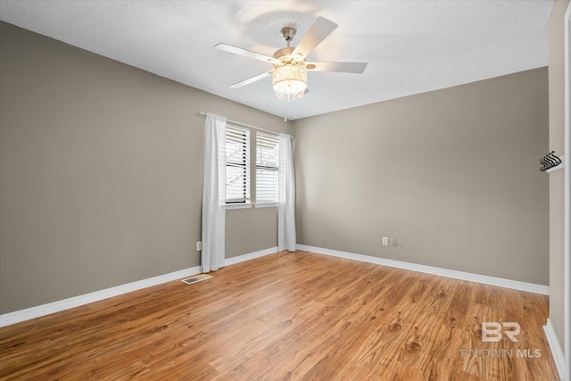 empty room featuring light wood-style floors, visible vents, baseboards, and a ceiling fan