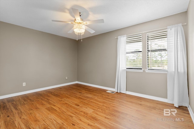 unfurnished room featuring baseboards, a ceiling fan, visible vents, and light wood-style floors