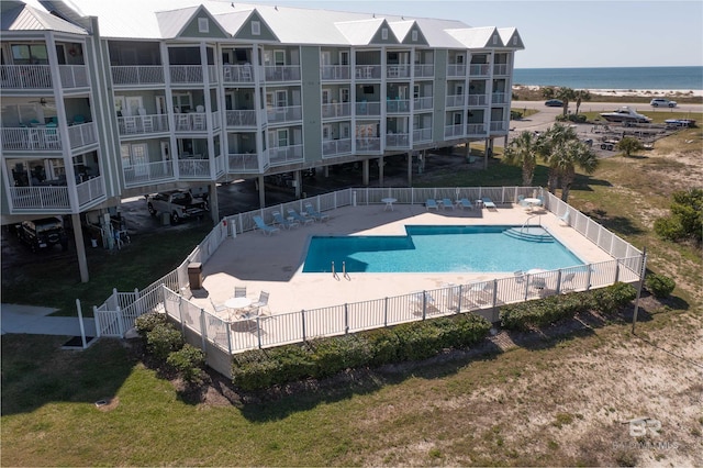 community pool featuring a patio area, a water view, and fence